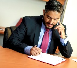 Illinois male paralegal taking notes on phone with client